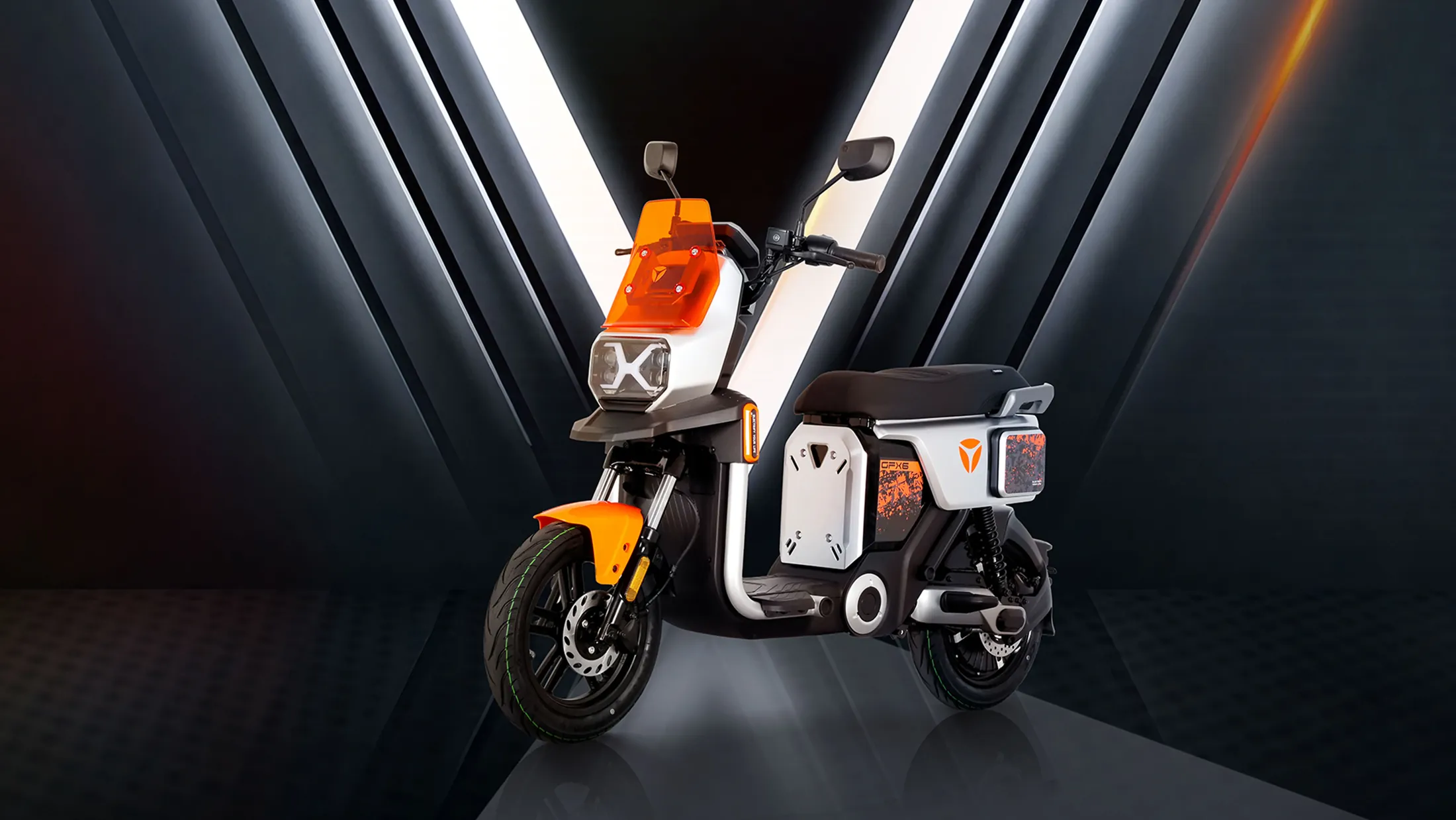 Vélo électrique YADEA GFX6 orange et blanc, dans un studio sombre traversé de faisceaux lumineux